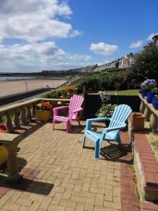 three chairs sitting on a patio near the beach at Captains Lodge in Newbiggin-by-the-Sea