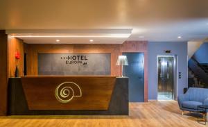 カゼルタにあるHotel Europa Art Casertaのホテルのロビーにはフロントデスクと青い椅子があります。