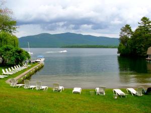 The Villas on Lake George في Diamond Point: مجموعة كراسي جالسة على العشب بجانب البحيرة