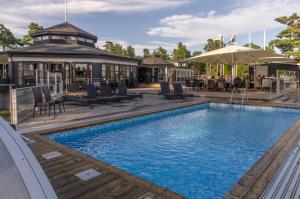 a pool at a hotel with chairs and tables at Strandby Villas Käringsund in Eckerö