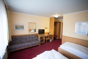 a hotel room with a couch and a television at Hotel Restaurant Zur Post Lohfelden in Kassel