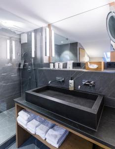 a bathroom with a black tub and a mirror at Hotel Staudacherhof History & Lifestyle in Garmisch-Partenkirchen