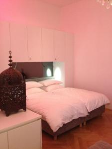 Schlafzimmer mit einem Bett mit weißer Bettwäsche und rosa Wänden in der Unterkunft Hoheschule Apartment Levade in Wien