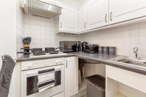 a kitchen with white cabinets and a stove and a sink at Guest Homes - New Street Apartment in Worcester