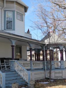 a white house with a blue porch and a tree at Market Street Inn in Taylorville