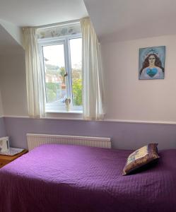 a bedroom with a purple bed with a window at Camelot Retreat - Tor View in Glastonbury