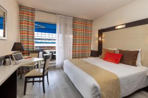una camera d'albergo con letto, scrivania e tavolo di The Originals City, Hôtel Galaxie, Nice Aéroport a Saint-Laurent-du-Var