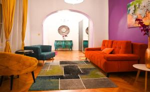 salon z pomarańczową kanapą i 2 krzesłami w obiekcie Breathtaking Suite Mozart w Wiedniu
