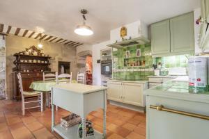 una cocina con armarios verdes y blancos y una mesa en Mas Jullian, en Graveson