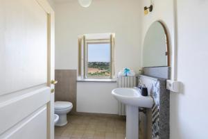 baño con lavabo y aseo y ventana en B&b San Rocco, en Celleno