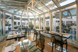 a restaurant with tables and chairs in a room with windows at The Street Milano Duomo | a Design Boutique Hotel in Milan