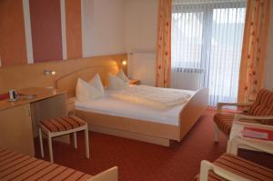 a hotel room with a bed and a chair at Königsteiner Hof in Königstein in der Oberpfalz