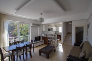 a living room with a table and chairs and a kitchen at Infinity Olympia Apartments in Oludeniz