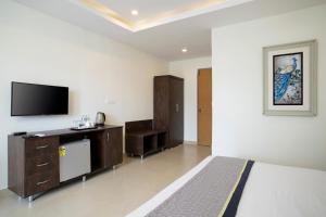a bedroom with a bed and a flat screen tv at La Vaiencia Beach Resort, Morjim Beach in Morjim