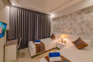 a hotel room with two beds and a tv at Nipola Hotel - Chợ Đêm Dương Đông Phú Quốc in Phú Quốc