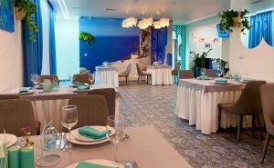a banquet room with tables and chairs with white tablecloths at Biruza Club in Petrivs'ke