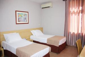 a hotel room with two beds and a window at Hotel Foz do Iguaçu in Foz do Iguaçu
