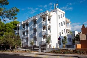 un edificio blanco con una torre encima en Apartamentos Top Secret Es Pujols - Formentera Vacaciones, en Es Pujols