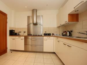 una cocina con armarios blancos y un aparato de acero inoxidable en Les Bateaux, en Poole