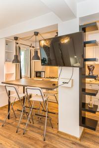 a kitchen with a table and a tv on a wall at Alessia Homes Coressi in Braşov +21 photos
