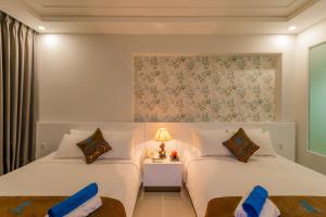 a bedroom with two beds and a table with a lamp at Nipola Hotel - Chợ Đêm Dương Đông Phú Quốc in Phú Quốc
