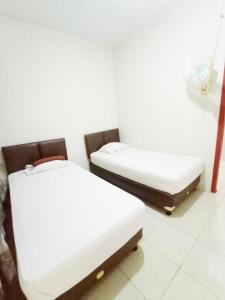 two beds in a room with white walls at Aqsa Guest House Banjarsari 