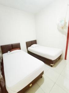 two beds in a room with white walls at Aqsa Guest House Banjarsari in Banjarsari