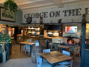 um restaurante com mesas e cadeiras e uma placa que lê sulco na parede em The George Inn Middle Wallop em Stockbridge