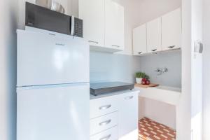 a kitchen with white cabinets and a refrigerator at Lido di Pomposa Flat a due passi dalla Spiaggia! in Lido di Pomposa