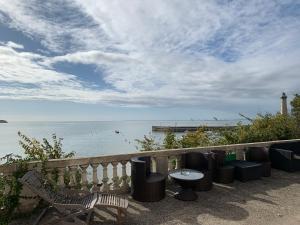 un patio con mesa, sillas y el océano en Villa TOUSVENTS, en Saint-Georges-de-Didonne