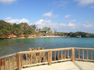 Media Luna Resort & Spa في First Bight: جسر فوق الماء مع منزل في الخلفية