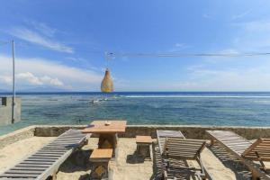 珀尼达岛Waterside inn Nusa Penida的海滩上的野餐桌椅和海洋