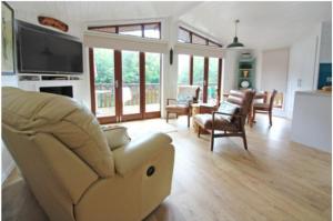 a living room with a couch and a television at Astbury Falls Luxury Retreats in Eardington +2 photos