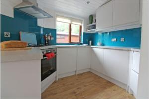 uma cozinha azul com armários brancos e paredes azuis em Astbury Falls Luxury Retreats em Eardington