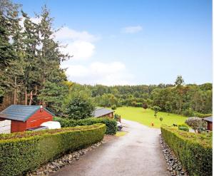 a driveway with a red house in a park at Astbury Falls Luxury Retreats in Eardington