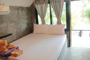 Bett in einem Zimmer mit einem großen Fenster in der Unterkunft Sichang Marina Resort in Ban Tha Thewawong