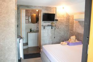 a small bedroom with a bed and a tv at Sichang Marina Resort in Ban Tha Thewawong