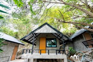 ein kleines Haus mit einer orangefarbenen Tür im Wald in der Unterkunft Sichang Marina Resort in Ban Tha Thewawong