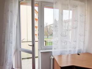 a window with white curtains and a wooden table at byt s balkonem in Žatec