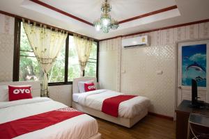 a bedroom with two beds and a chandelier at OYO 402 Raknatee Resort in Nakhon Pathom