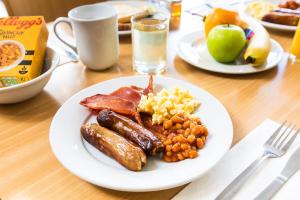 un piatto di prodotti per la colazione con uova di salsiccia, pancetta e frutta di Holiday Inn Express Norwich, an IHG Hotel a Norwich