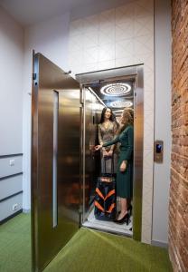 two women are standing inside of an elevator at Four Rooms City in Kharkiv