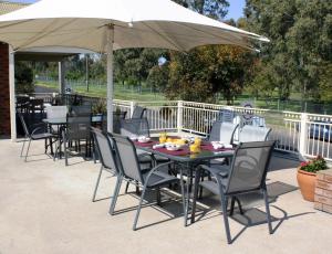 a table and chairs under an umbrella on a patio at Golf Links Motel in Tamworth