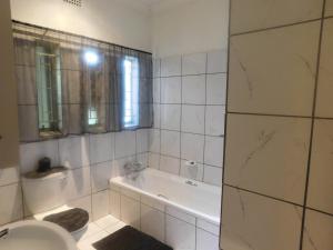 Baño blanco con bañera y lavamanos en Fouriestreet 199 Bed and Breakfast en Mokopane