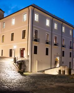 a large white building on a cobblestone street at Dimora de Matera Luxury Suites in Cosenza