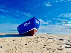 um barco azul sentado numa praia de areia em Hotel Willa Złota em Karwia