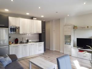 a kitchen with white cabinets and a living room at Apartamentos Aranda - La Villa in Aranda de Duero