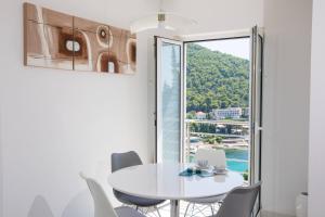 a white dining room with a table and chairs and a window at Apartment Vista 2 in Dubrovnik