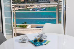 een witte tafel met twee kopjes en een paar schoenen bij Apartment Vista 2 in Dubrovnik