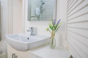 a bathroom with a sink and a vase with flowers at Detached Coach House near Principality Stadium in Cardiff in Cardiff +18 photos